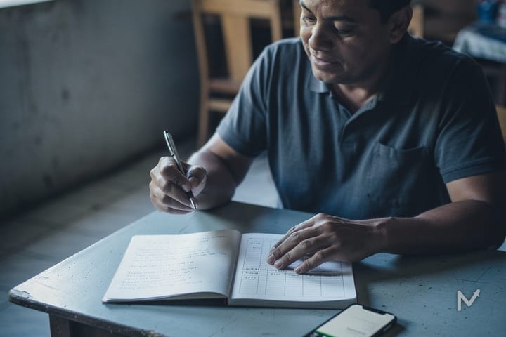 Autônomo controlando o fluxo de caixa do seu negócio em um caderno e no celular